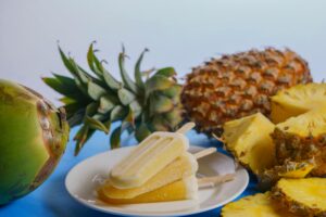 Refreshing tropical popsicles on a plate with coconut and pineapple slices.