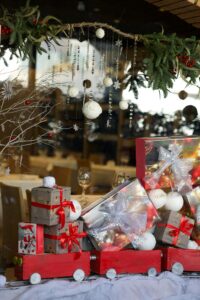 Red toy train laden with gift boxes and Christmas ornaments in a cozy festive setting.