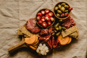 High angle view of a rustic charcuterie board featuring cheeses, meats, crackers, and pickles.