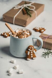 Warm and inviting winter scene featuring hot cocoa with marshmallows, gingerbread cookies, and gift boxes.